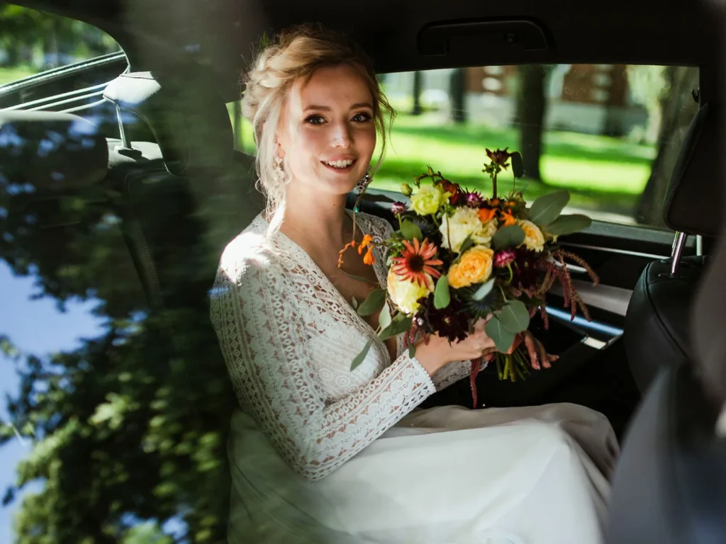 Brud sidder i bilen med en smuk blomsterbuket, klar til bryllupsceremonien, fotograferet af bryllupsfotograf på Sjælland nær København.