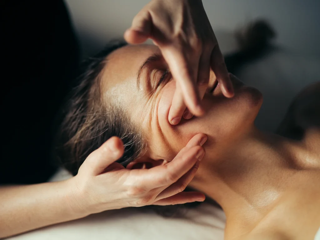 Nærbillede af en klient, der nyder en afslappende ansigtsmassage i professionelle omgivelser.