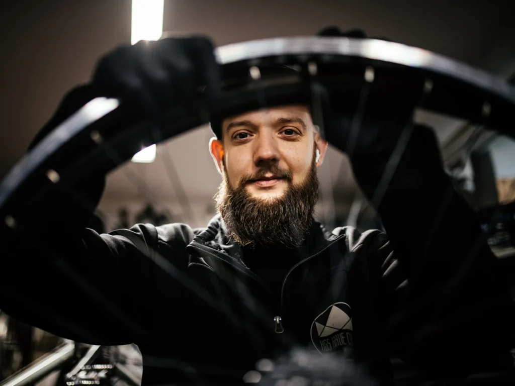 Cykelmekaniker fotograferet gennem et cykelhjul i værkstedet.