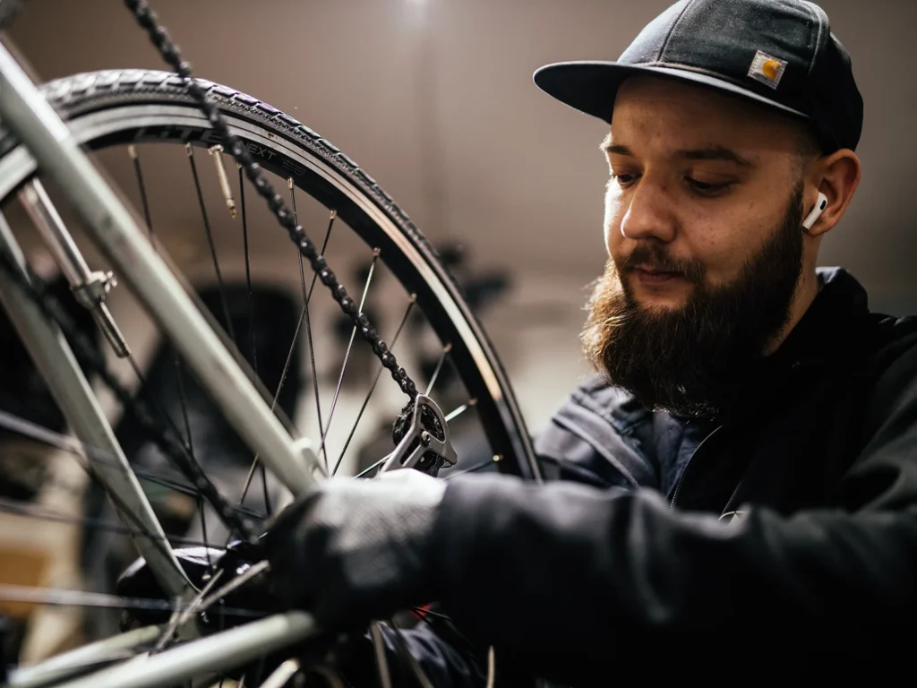 Nærbillede af en cykelmekaniker, der arbejder på en cykelkæde.