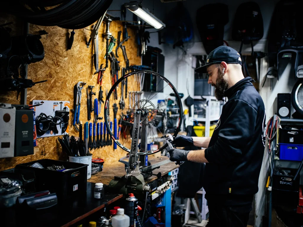 Professionel cykelmekaniker justerer et cykelhjul i sit velorganiserede værksted.