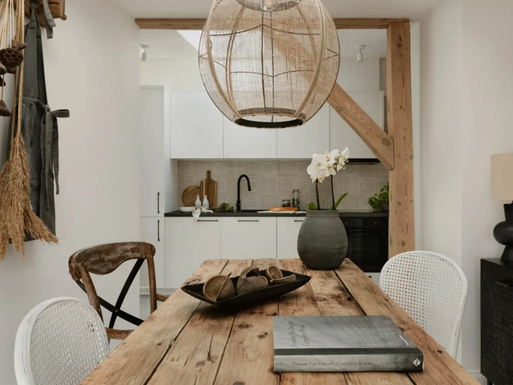 Rustikt og moderne spiseområde med synlige træelementer og en stilren køkkenbaggrund.