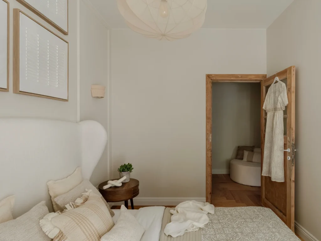 Lyst og elegant soveværelse med naturlige materialer og en rustik dør, der skaber en varm atmosfære.