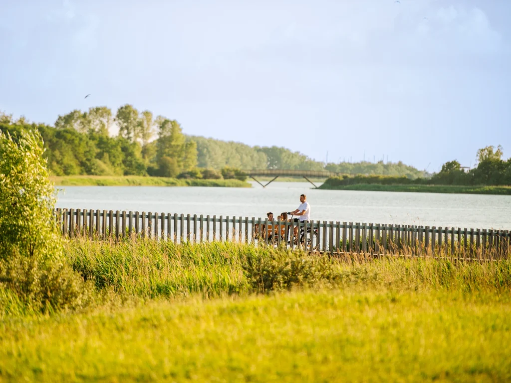 Familie på cykeltur ved naturskøn sø i Sjælland – autentisk familiefotografering i København og omegn.